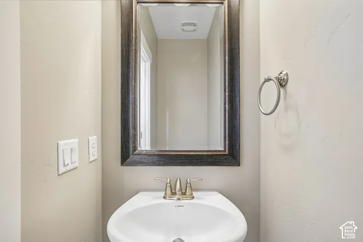 Pedestal sink with a brushed nickel faucet, framed mirror, and coordinating towel ring