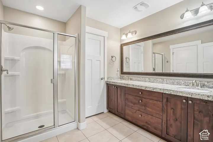 Dual sink vanity with stone-finish countertop, wood-finish cabinetry, and a large framed mirror