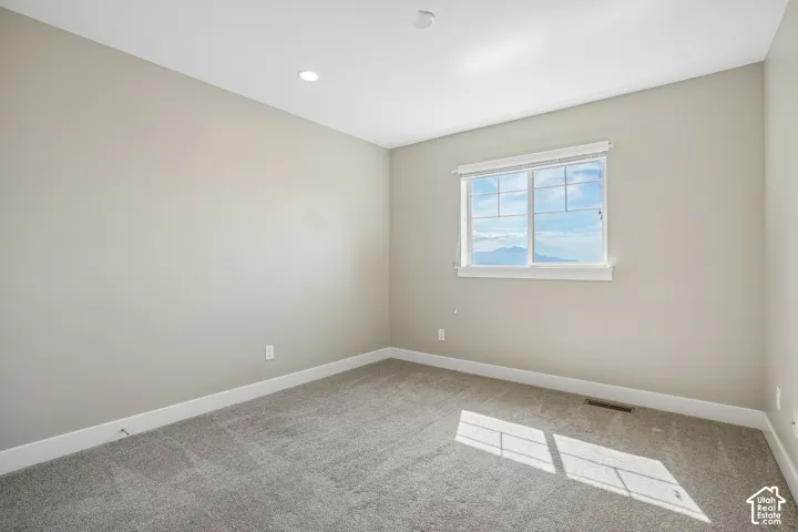Recessed lighting, neutral wall tones, window with white trim, and gray carpet flooring