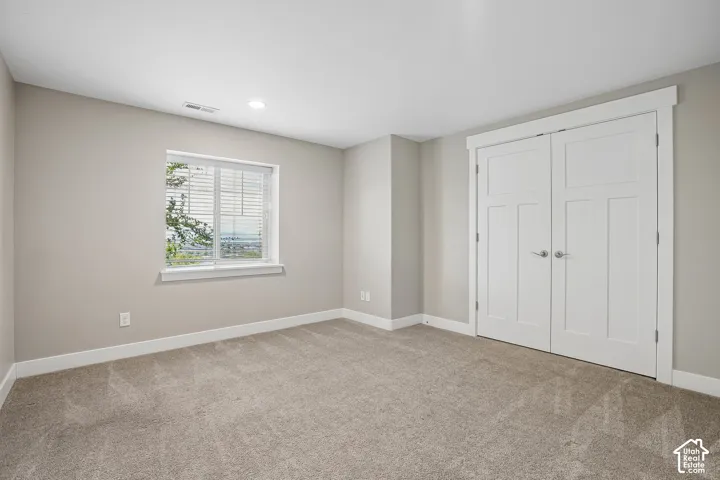 Neutral-toned carpeting, white trim, recessed lighting, and a double-panel closet door