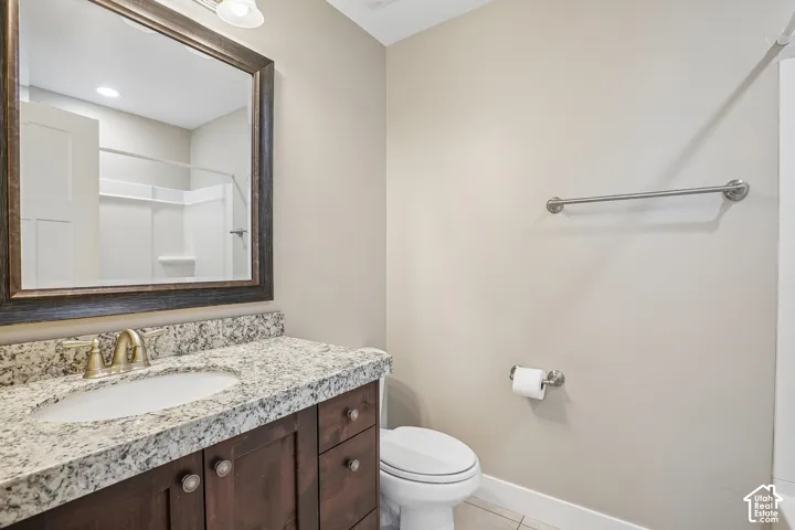 Wood-finish vanity with a speckled countertop, undermount sink, and brushed brass-finish faucet