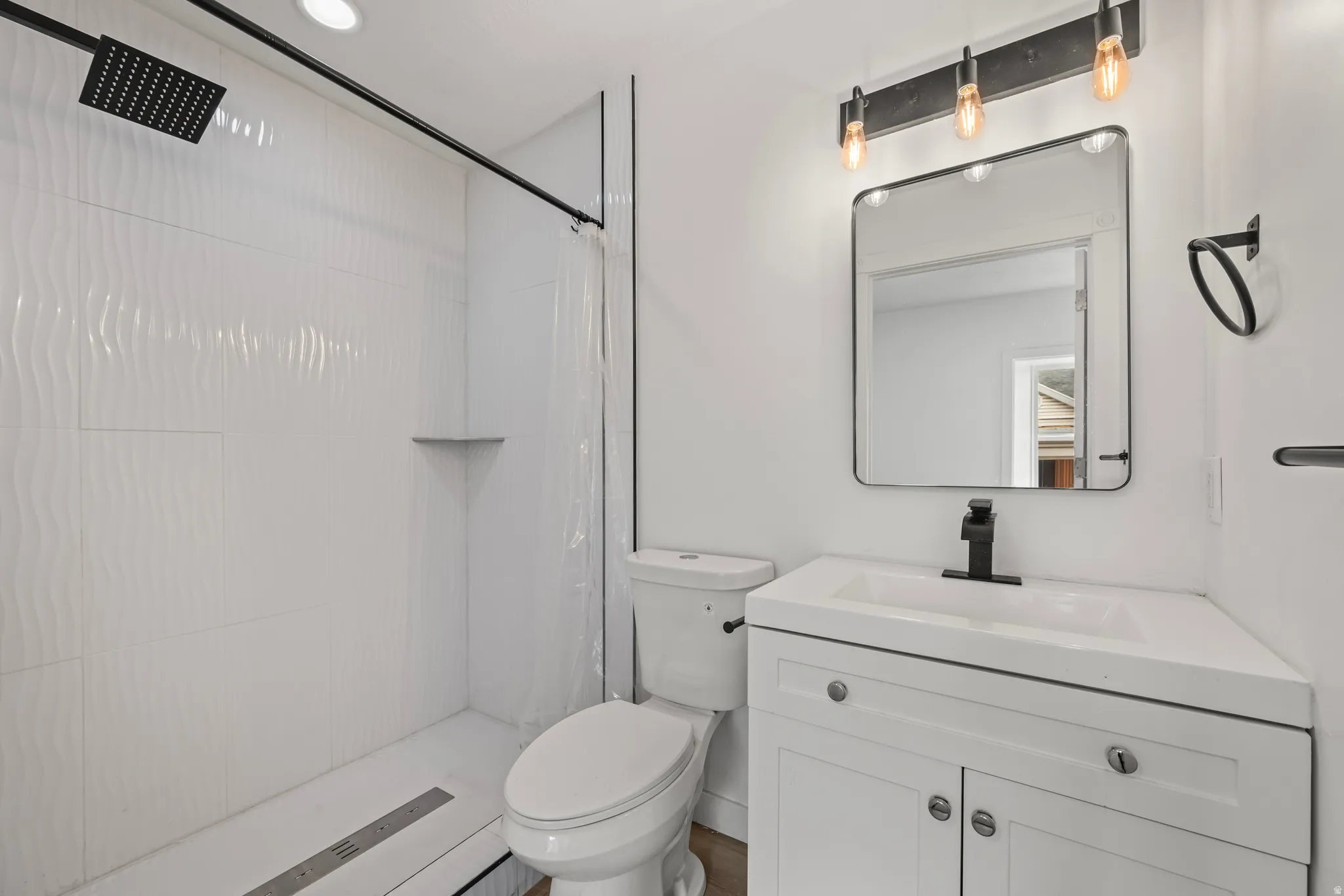 White vanity with integrated sink, black fixtures, and a rectangular framed mirror