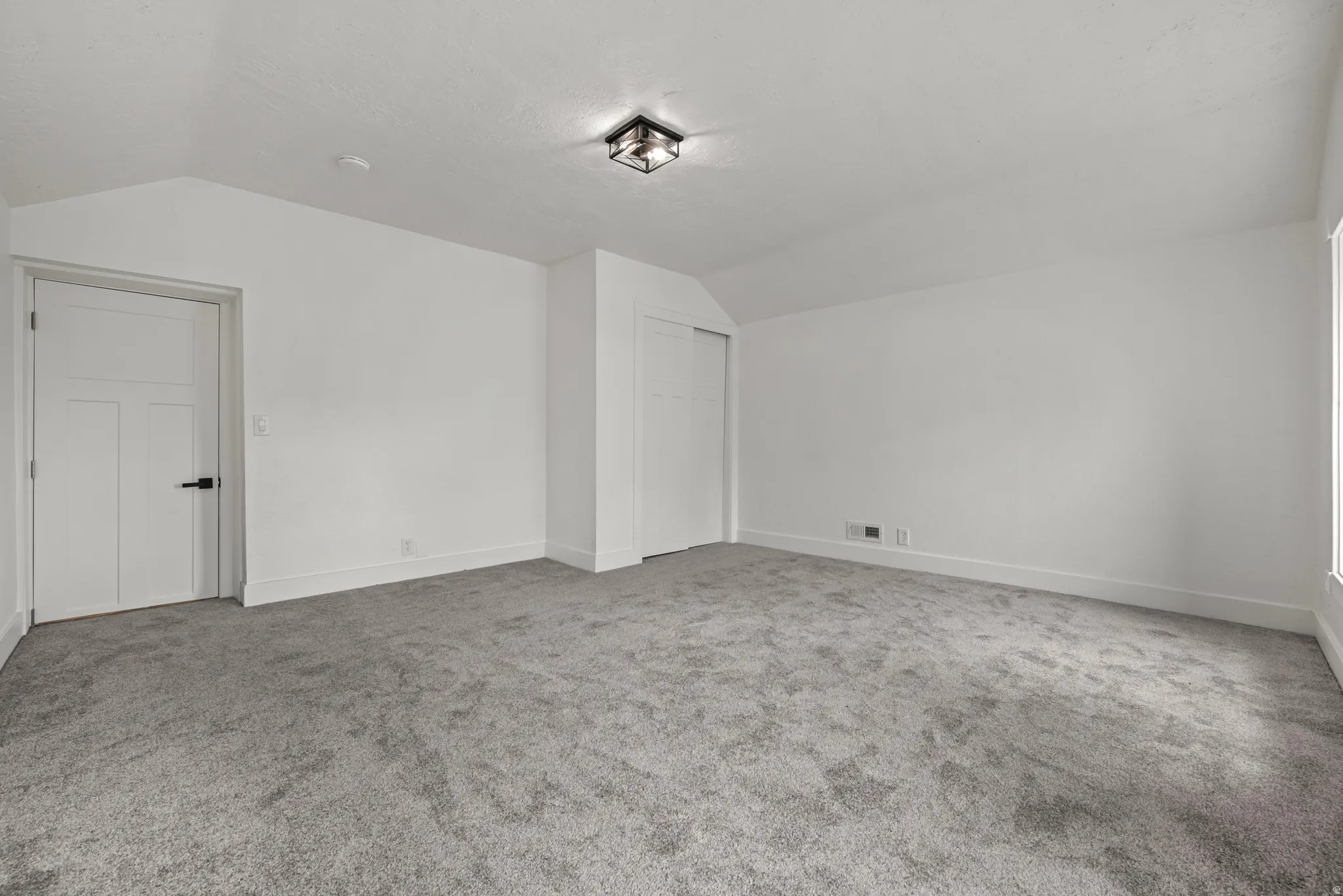 Spacious room featuring neutral carpeting, white walls, and a contemporary flush-mount ceiling light