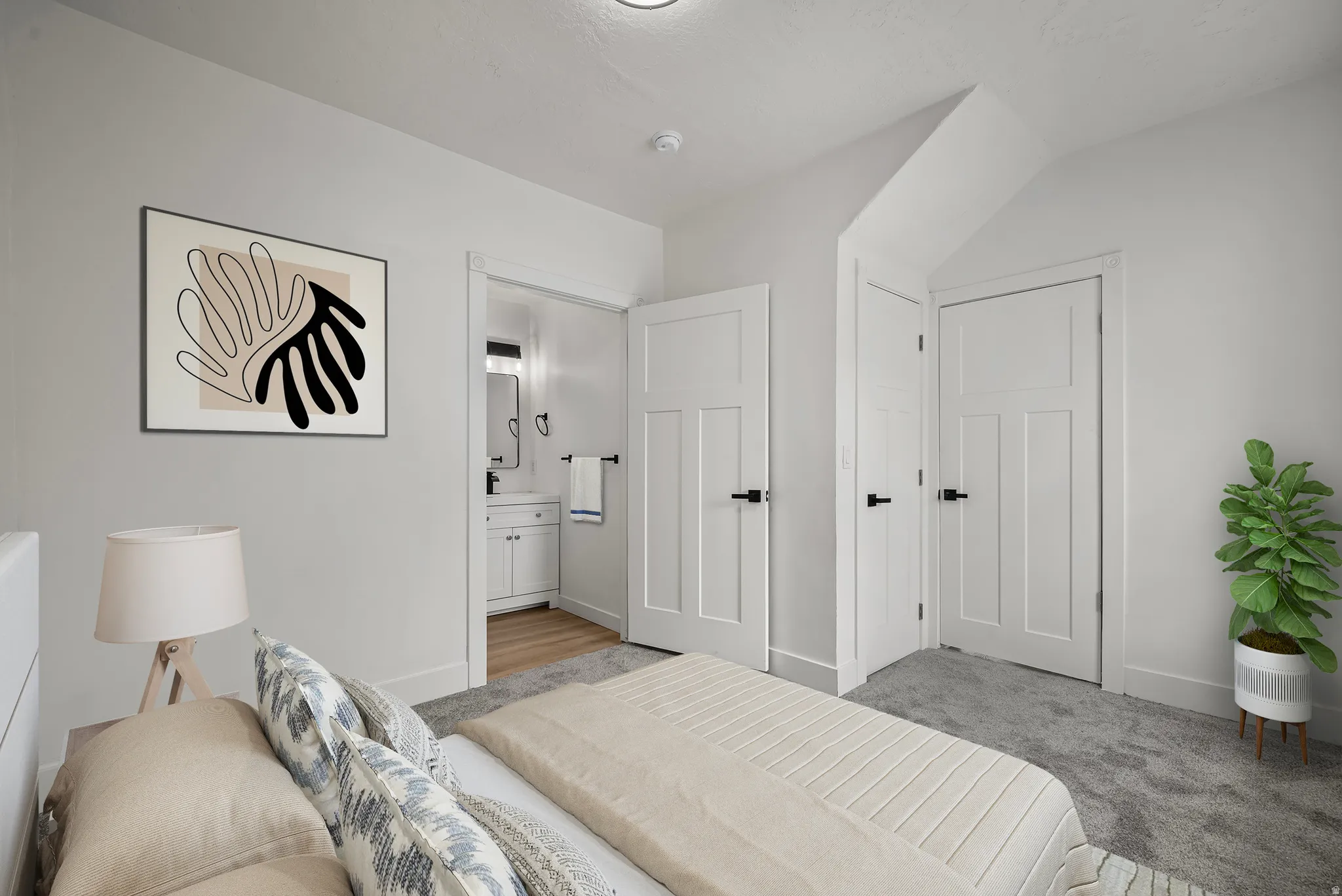 Plush carpet flooring, white interior doors with black hardware, and an en-suite bathroom featuring a vanity with a rectangular sink