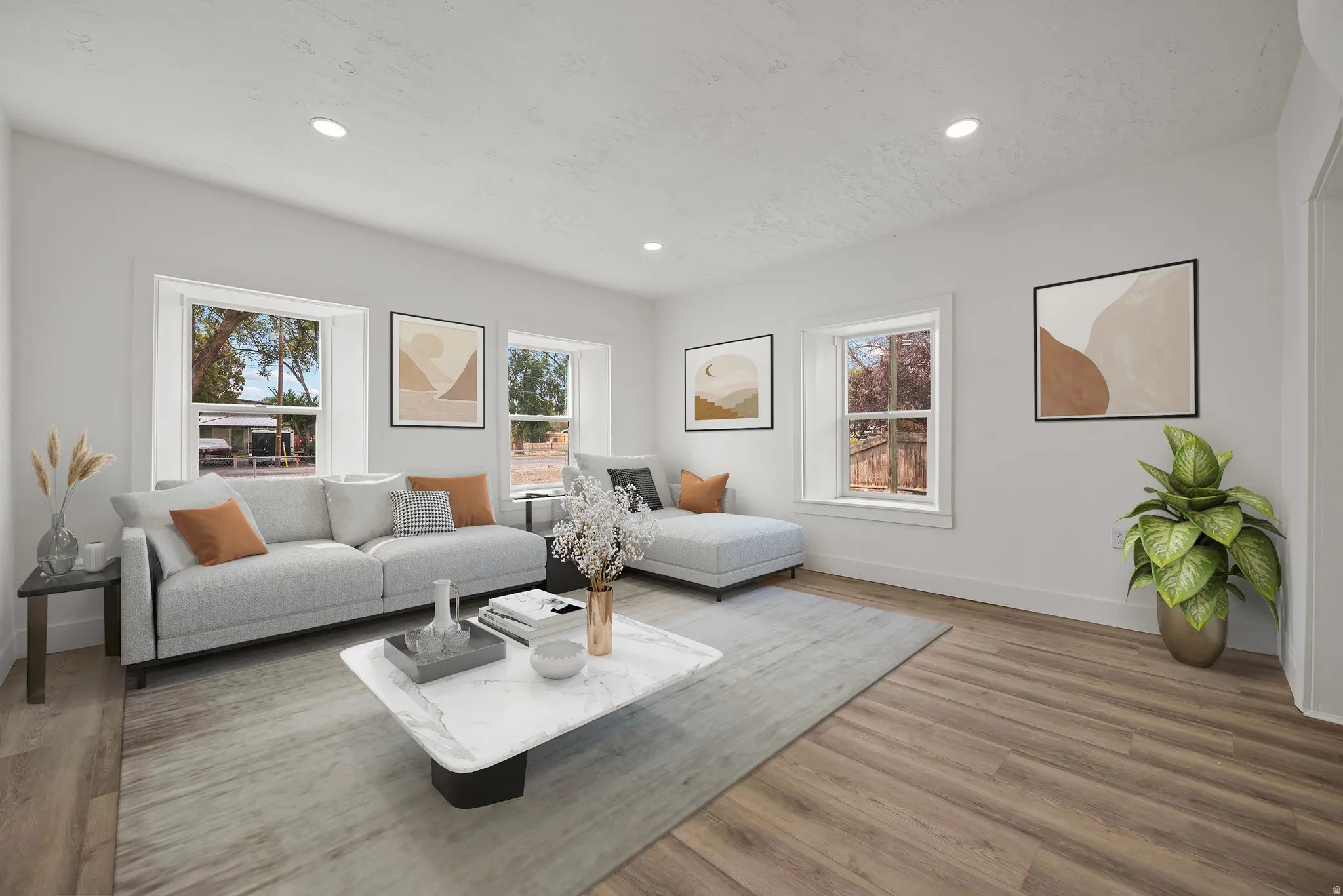 Recessed lighting illuminates the living space featuring wood-finish flooring and multiple windows with white trim