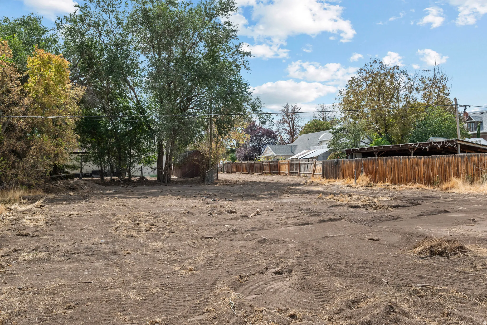 Cleared lot with established trees and wood fencing