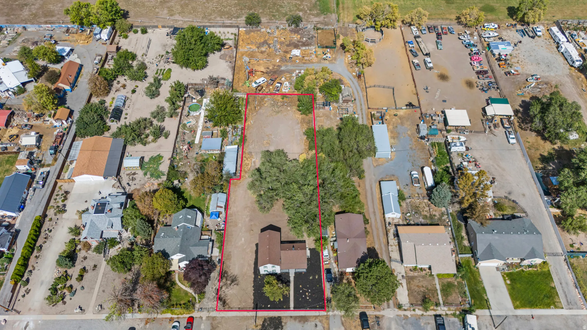 Expansive lot with varied terrain, featuring mature trees and established structures