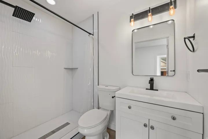 White vanity with integrated sink, black fixtures, and a rectangular framed mirror