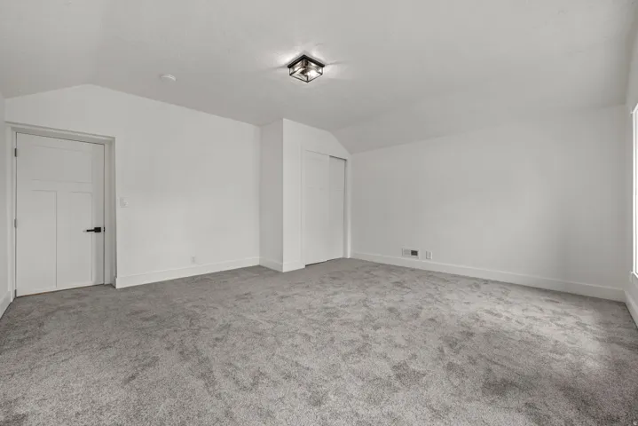 Spacious room featuring neutral carpeting, white walls, and a contemporary flush-mount ceiling light