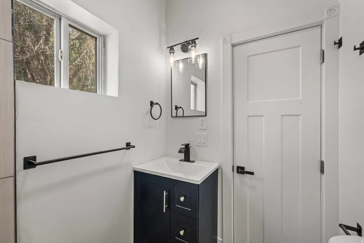 Window with natural light, dark blue vanity with white countertop, black fixtures, and white paneled door