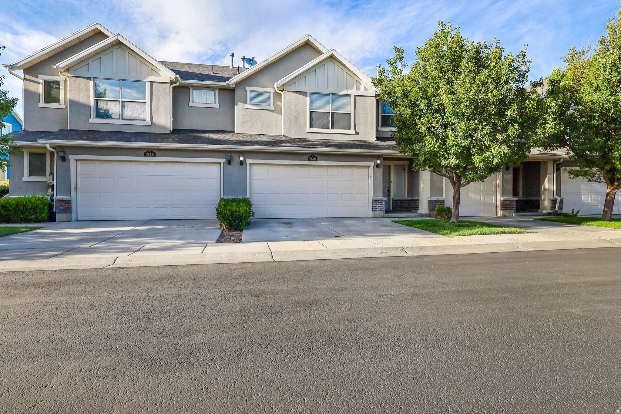 Contemporary townhouse exterior featuring a two-car garage, stucco siding, and stone accents