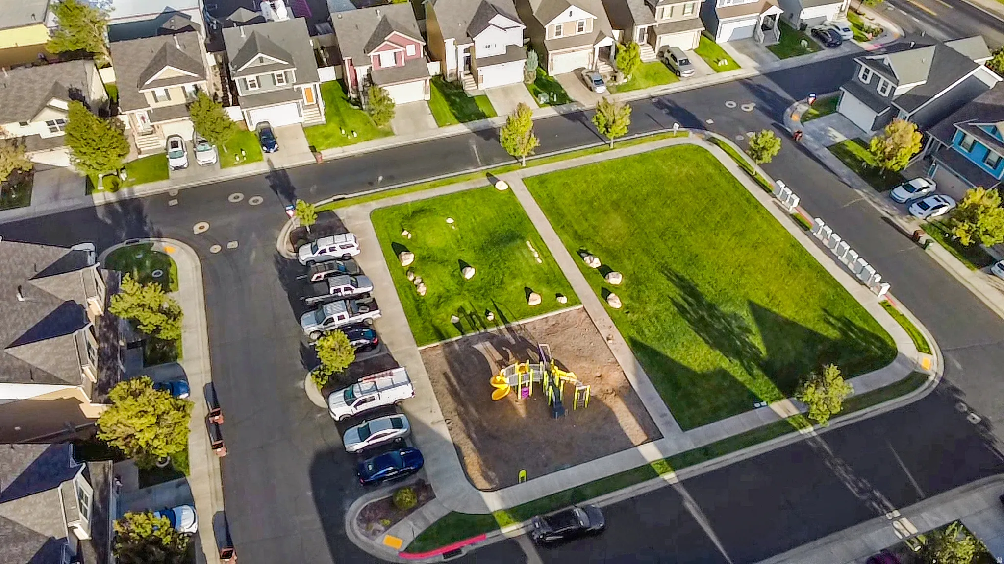 Neighborhood park with a playground, expansive green space, surrounding sidewalks, and mature trees