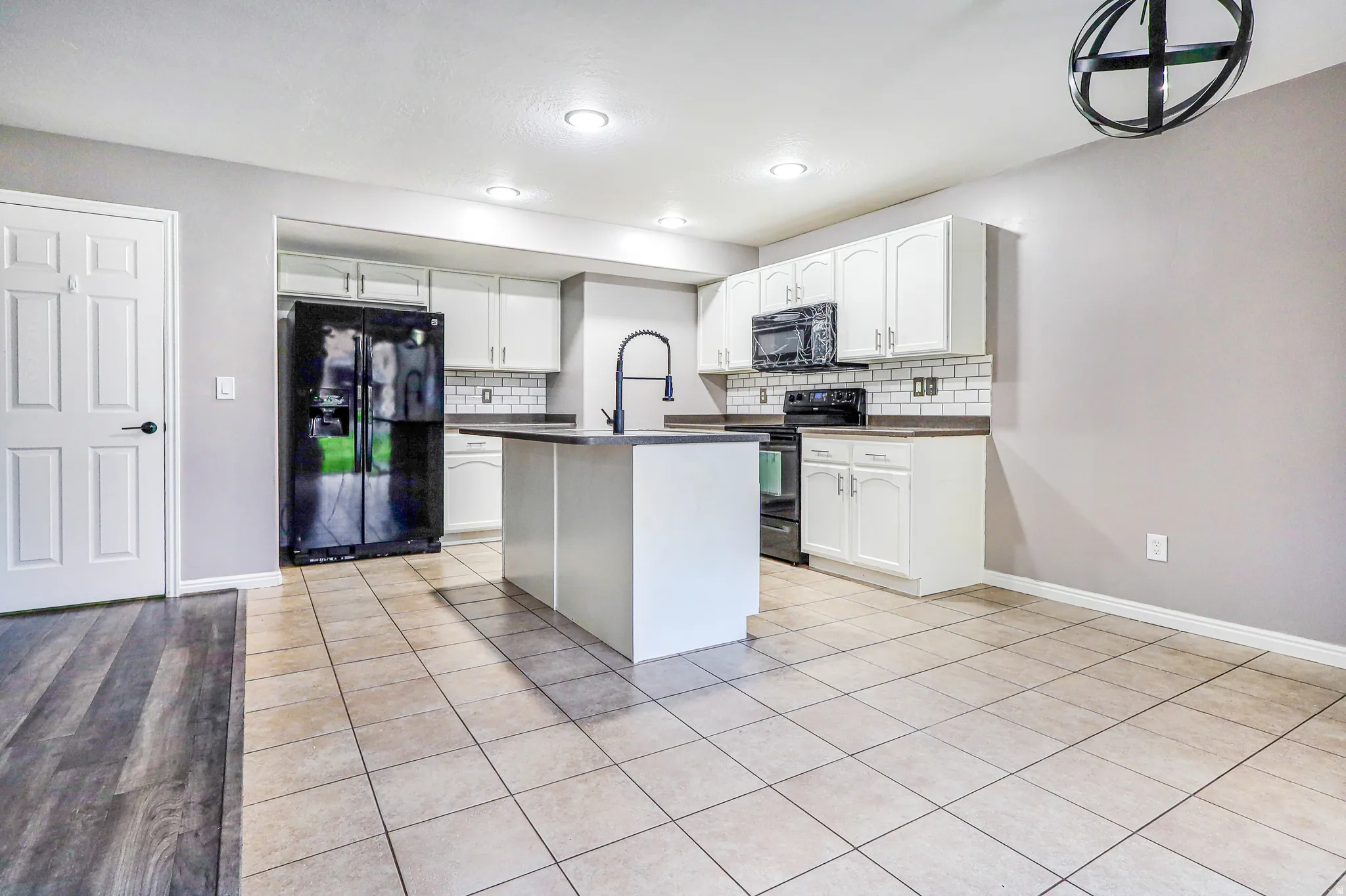 Kitchen featuring white shaker cabinetry, dark countertops, a central island, and stainless steel appliances