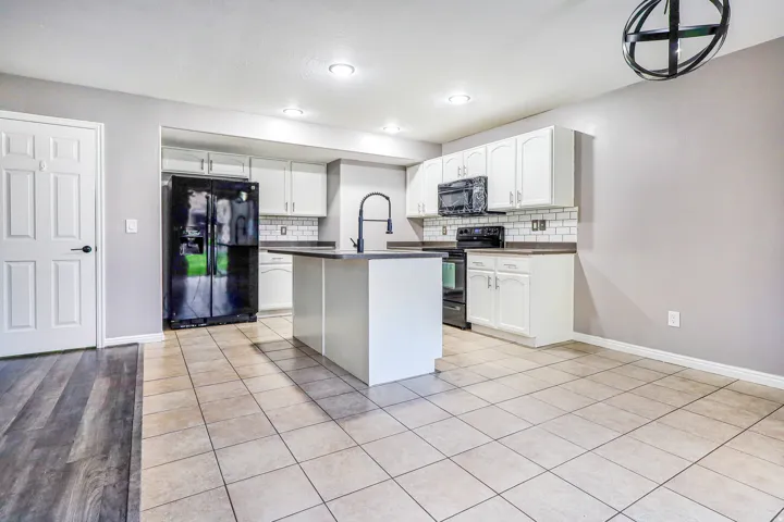 Kitchen featuring white shaker cabinetry, dark countertops, a central island, and stainless steel appliances
