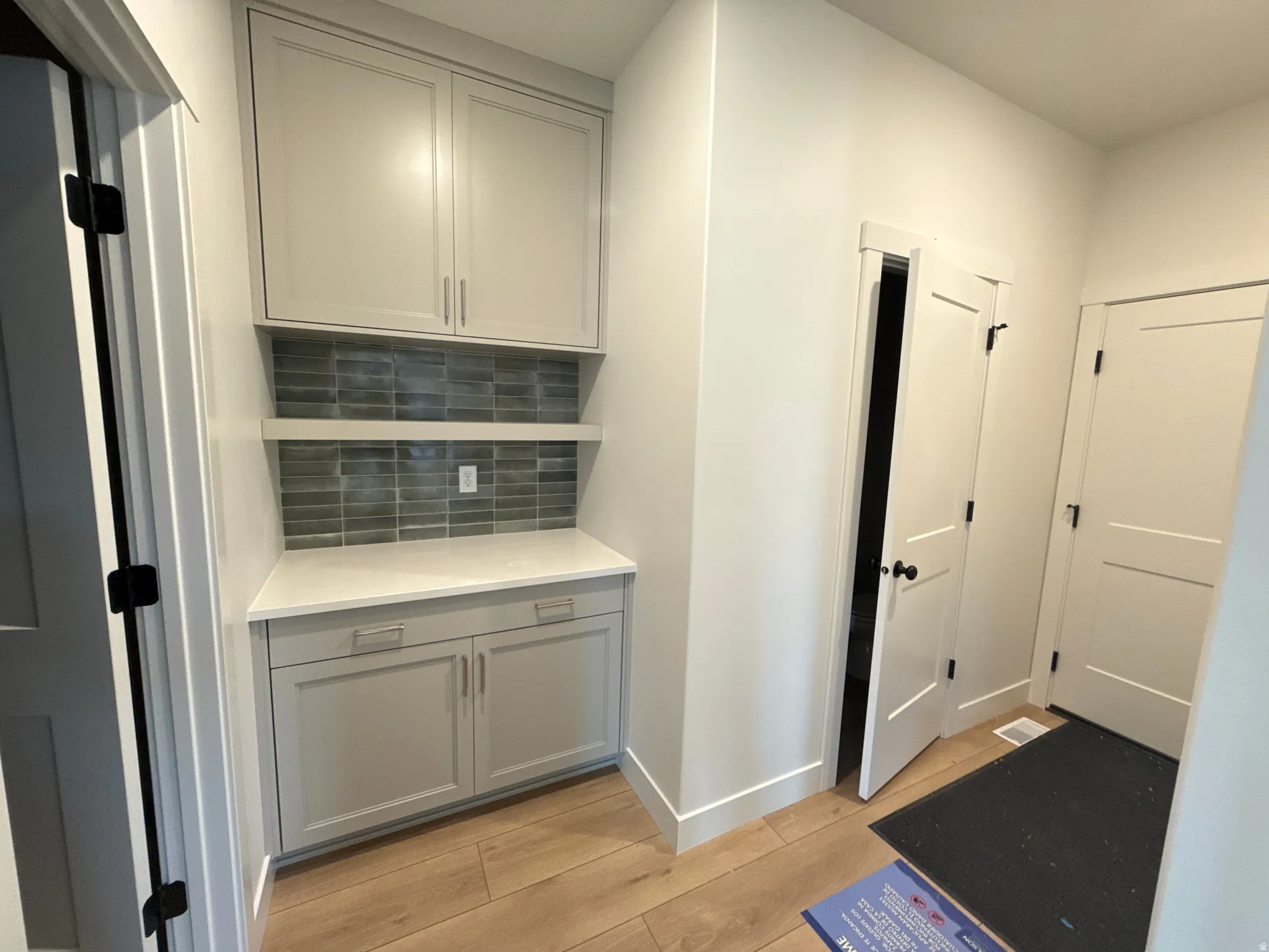 Built-in cabinetry with light gray shaker-style doors, a white countertop, and a tiled backsplash