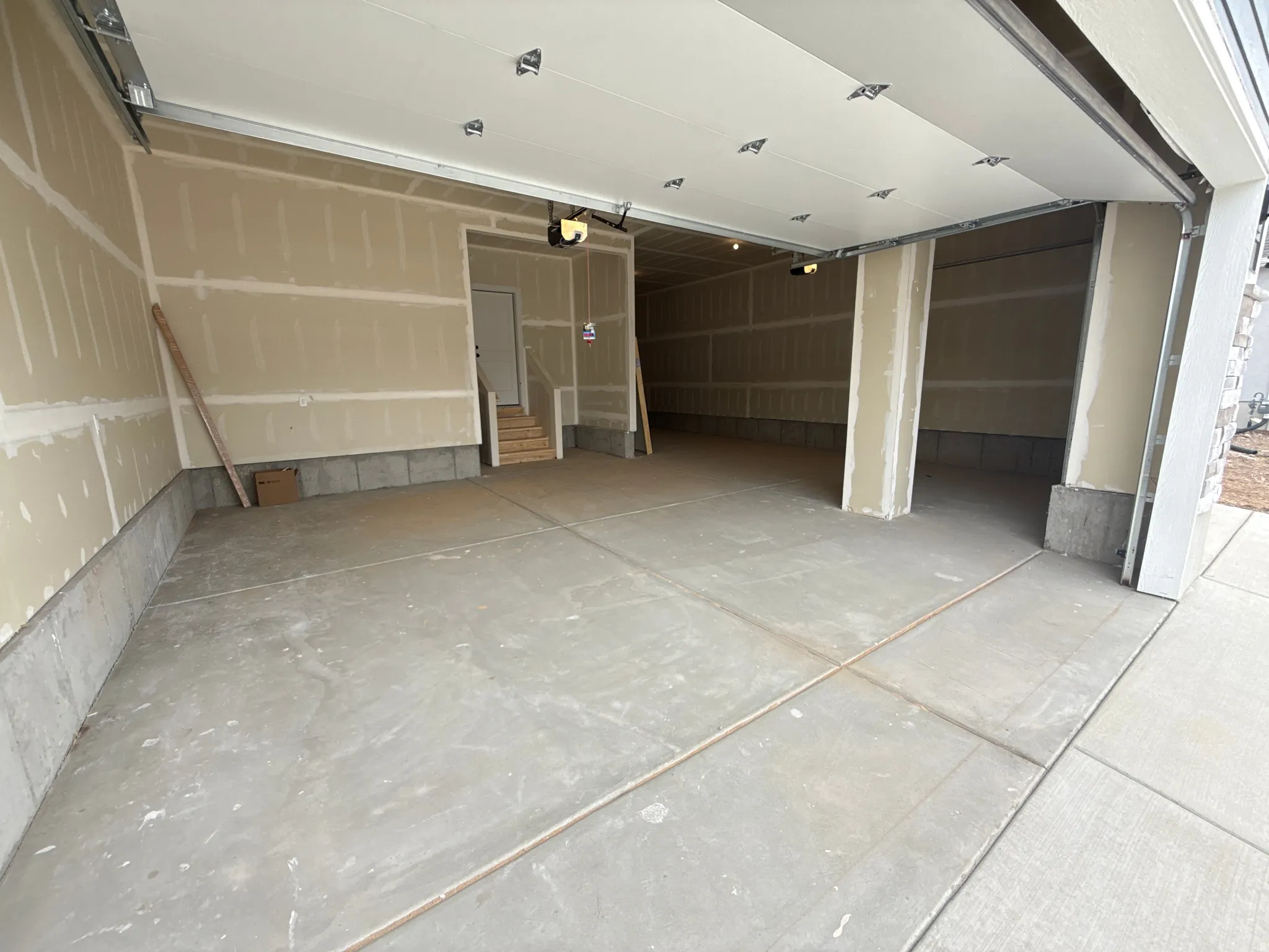 Spacious garage with concrete flooring, automatic overhead door, and interior access door