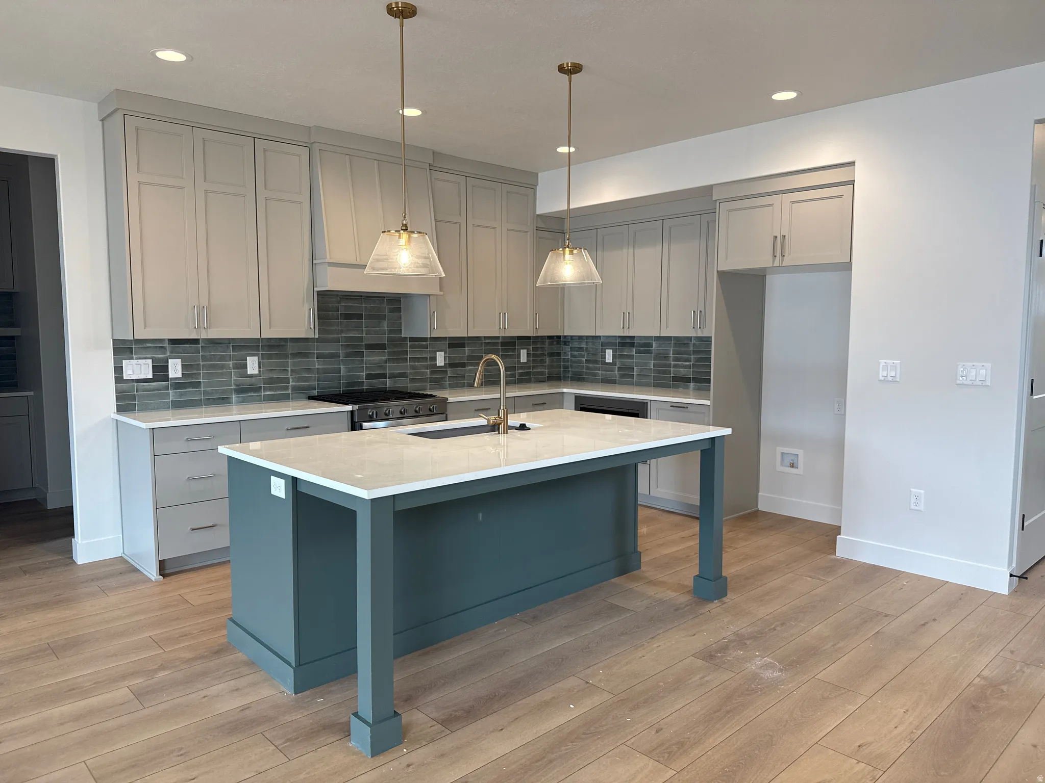 Open-concept kitchen featuring an island with a contrasting base, light-toned cabinetry, subway tile backsplash, and wood-finish flooring