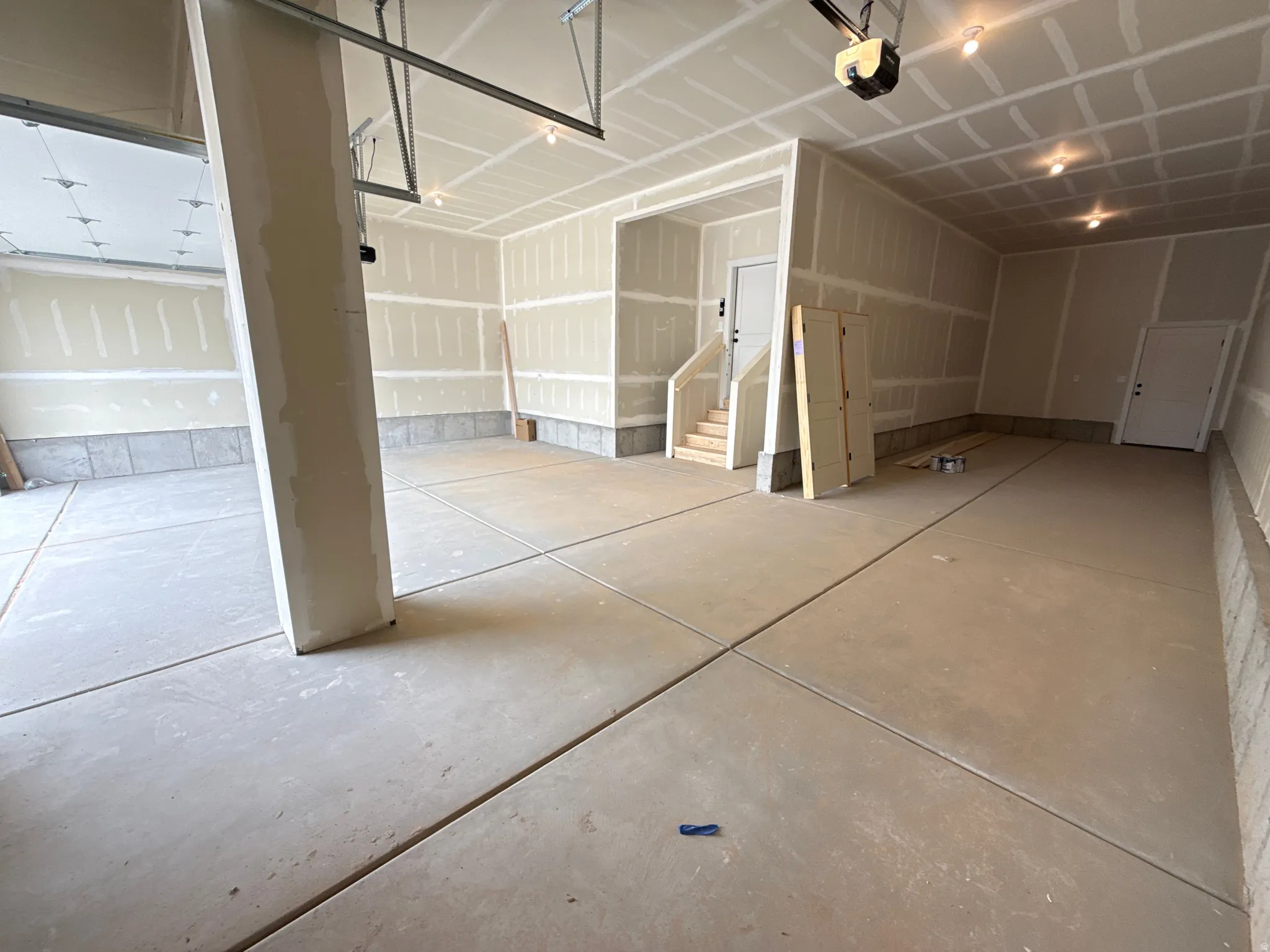Spacious garage featuring concrete flooring, unpainted drywall, and recessed lighting