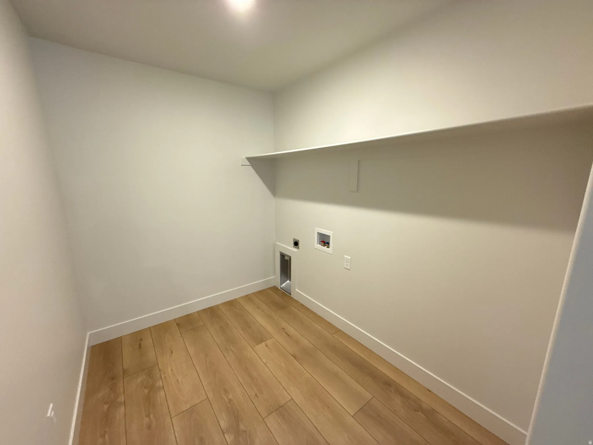 Wood-finish flooring, overhead built-in shelving, and recessed ceiling lighting