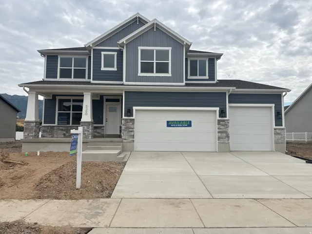 Two-story residence featuring a blue siding exterior with white trim, stone accents, a covered front porch, and a two-car garage