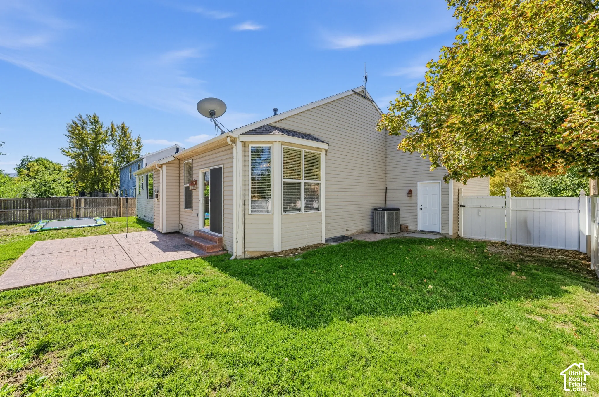 Expansive backyard featuring a manicured lawn, concrete patio, and bay window