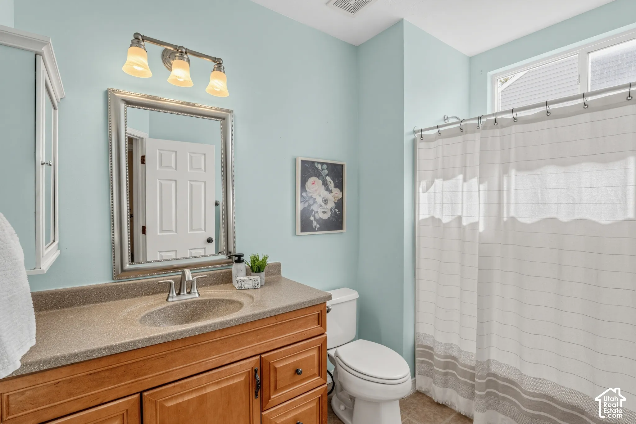Wood-finish vanity with a single basin sink and brushed nickel faucet