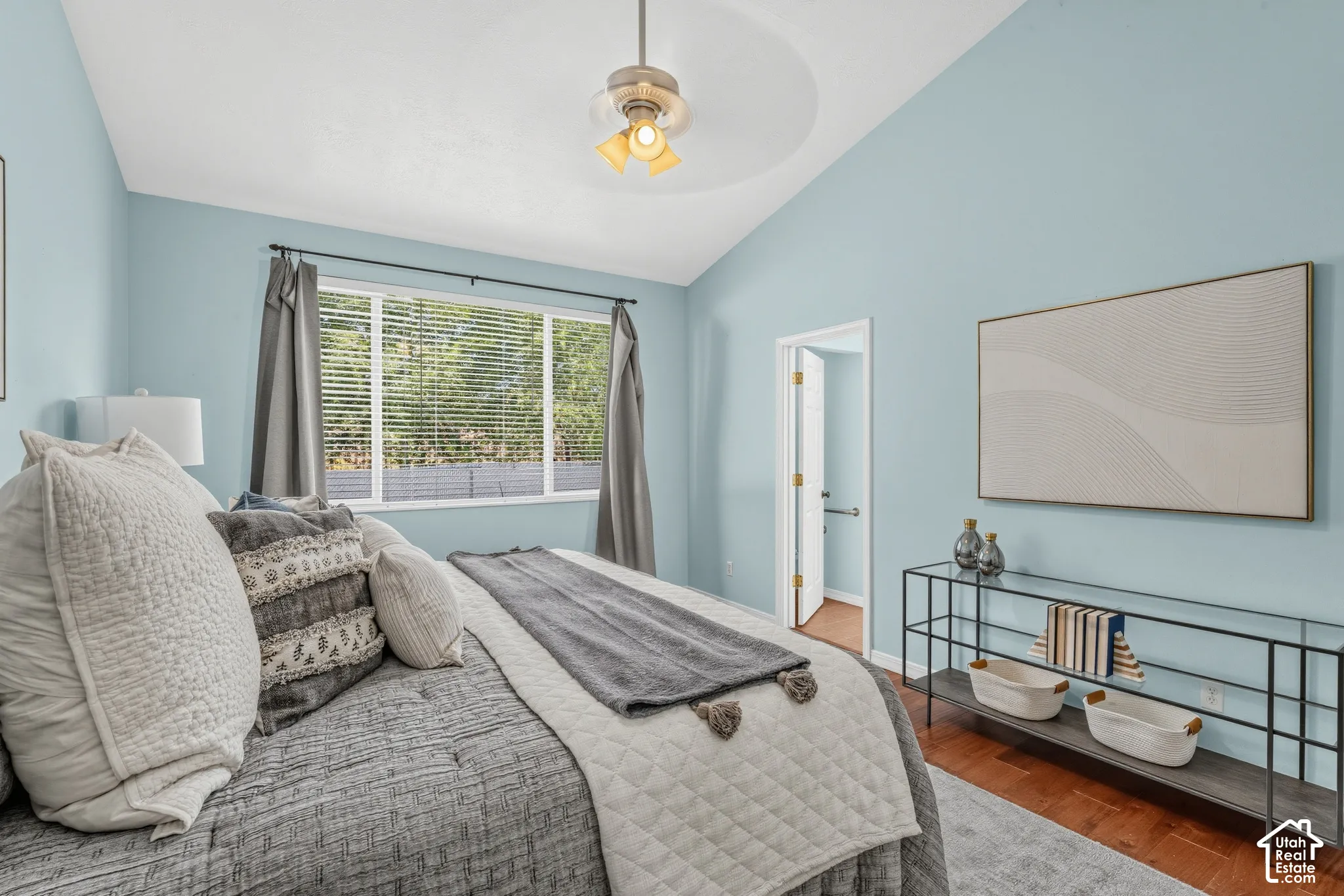 Vaulted ceiling with a ceiling fan, wood-finish flooring, and a window with blinds