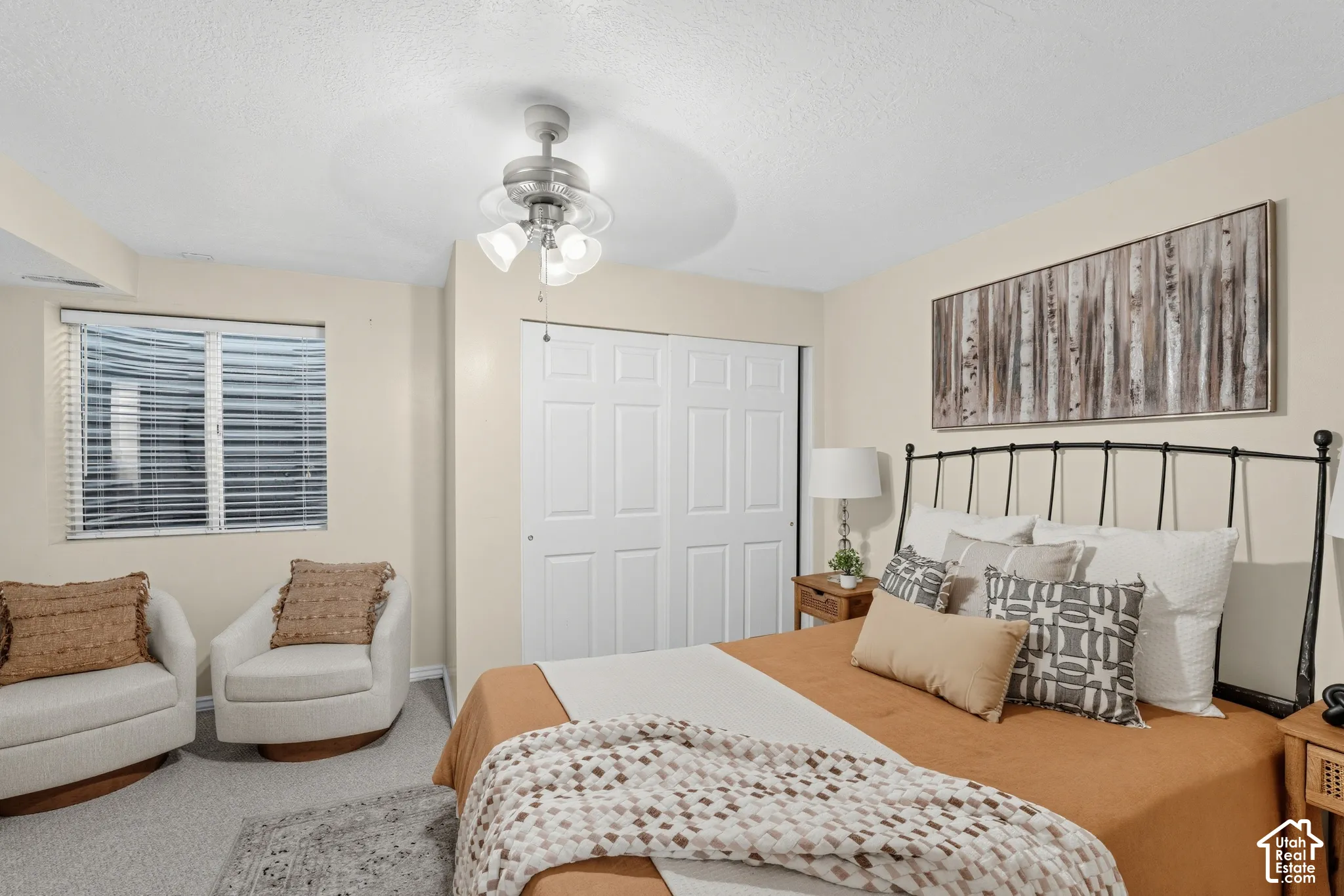 Carpeted room featuring a ceiling fan with light fixture, window with horizontal blinds, and a built-in bi-fold closet