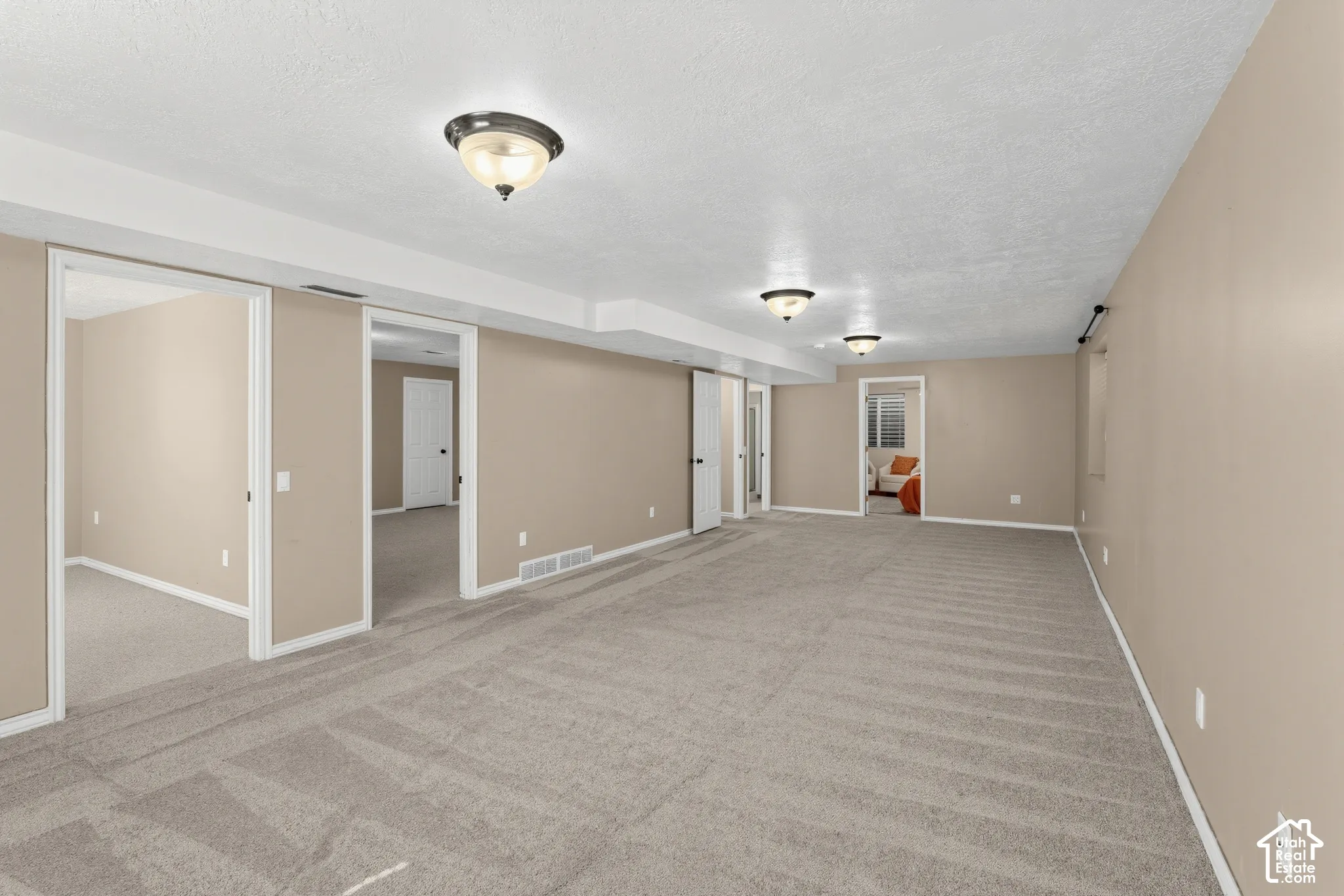 Expansive finished lower level featuring recessed lighting, light-colored carpeting, multiple doorways, and neutral wall tones