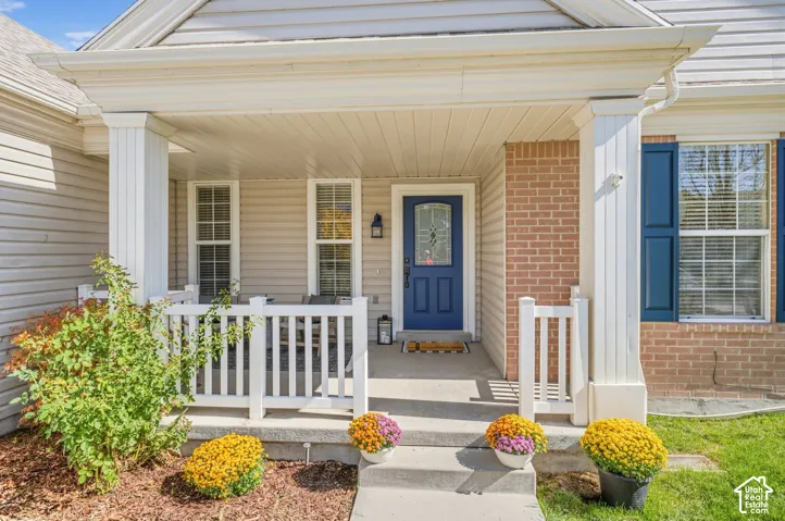 Covered front porch with white railing, brick and siding exterior, blue entry door with decorative glass, and blue window shutters