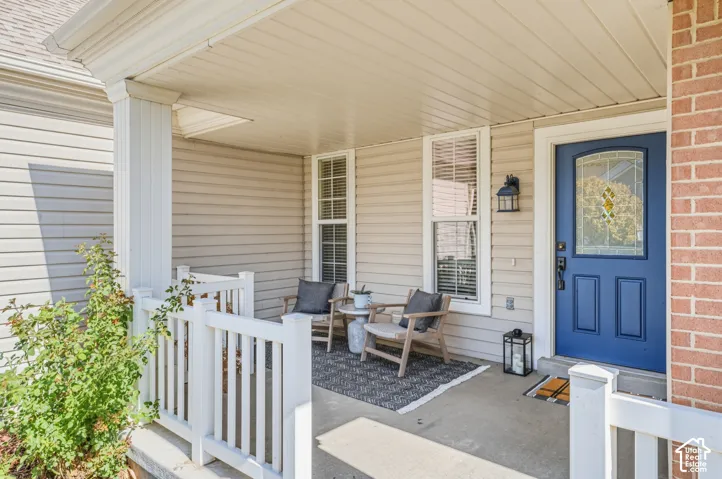 Covered porch with white columns, horizontal siding, a blue entry door with decorative glass, and a brick exterior accent