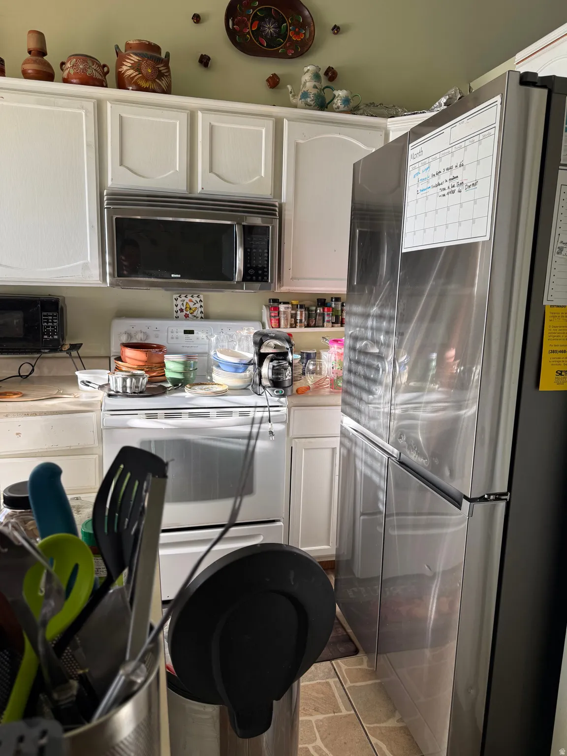 White cabinetry with brushed nickel hardware, stainless steel microwave, and white range