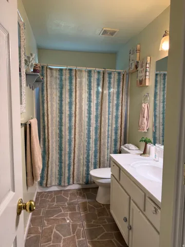 Bathroom with irregular-shaped floor tiling, single vanity with integrated sink, and wall-mounted light fixture
