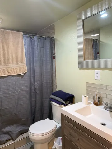 Built-in vanity with integrated sink, wood-finish cabinetry, and horizontal tile backsplash