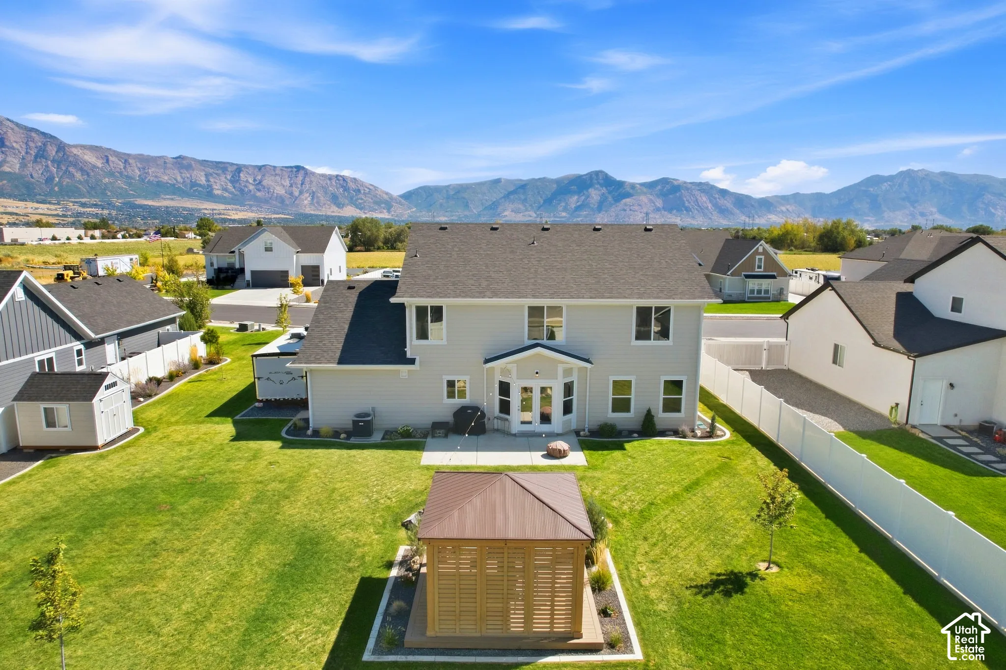 Expansive backyard featuring a manicured lawn, established landscaping, and a freestanding gazebo