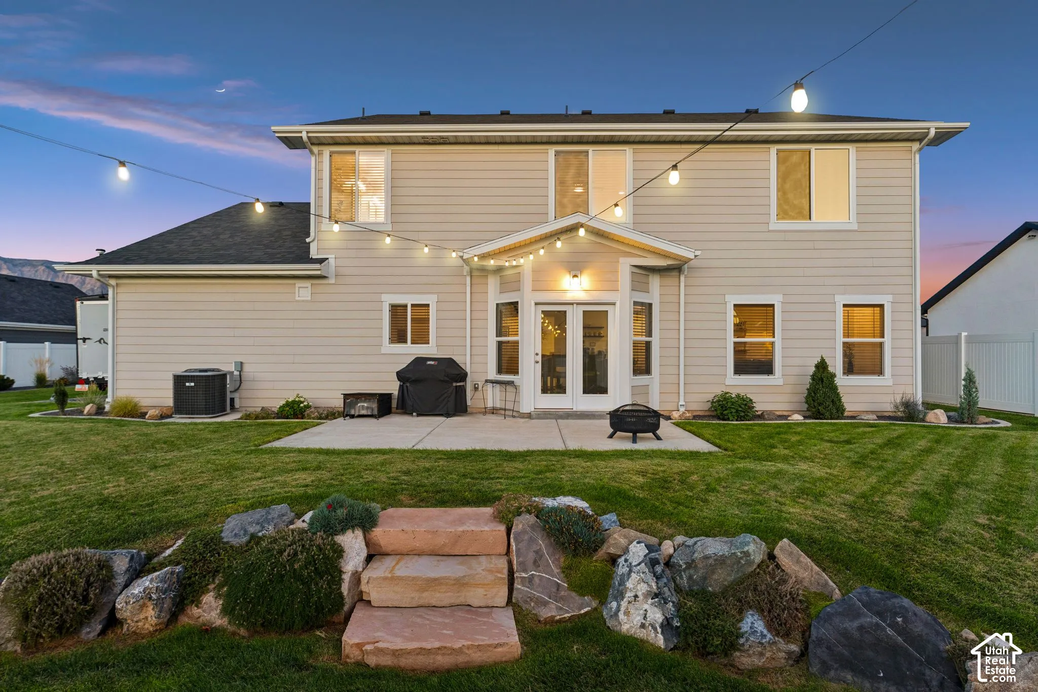 Rear exterior featuring light-colored siding, a covered patio, and dual glass French doors