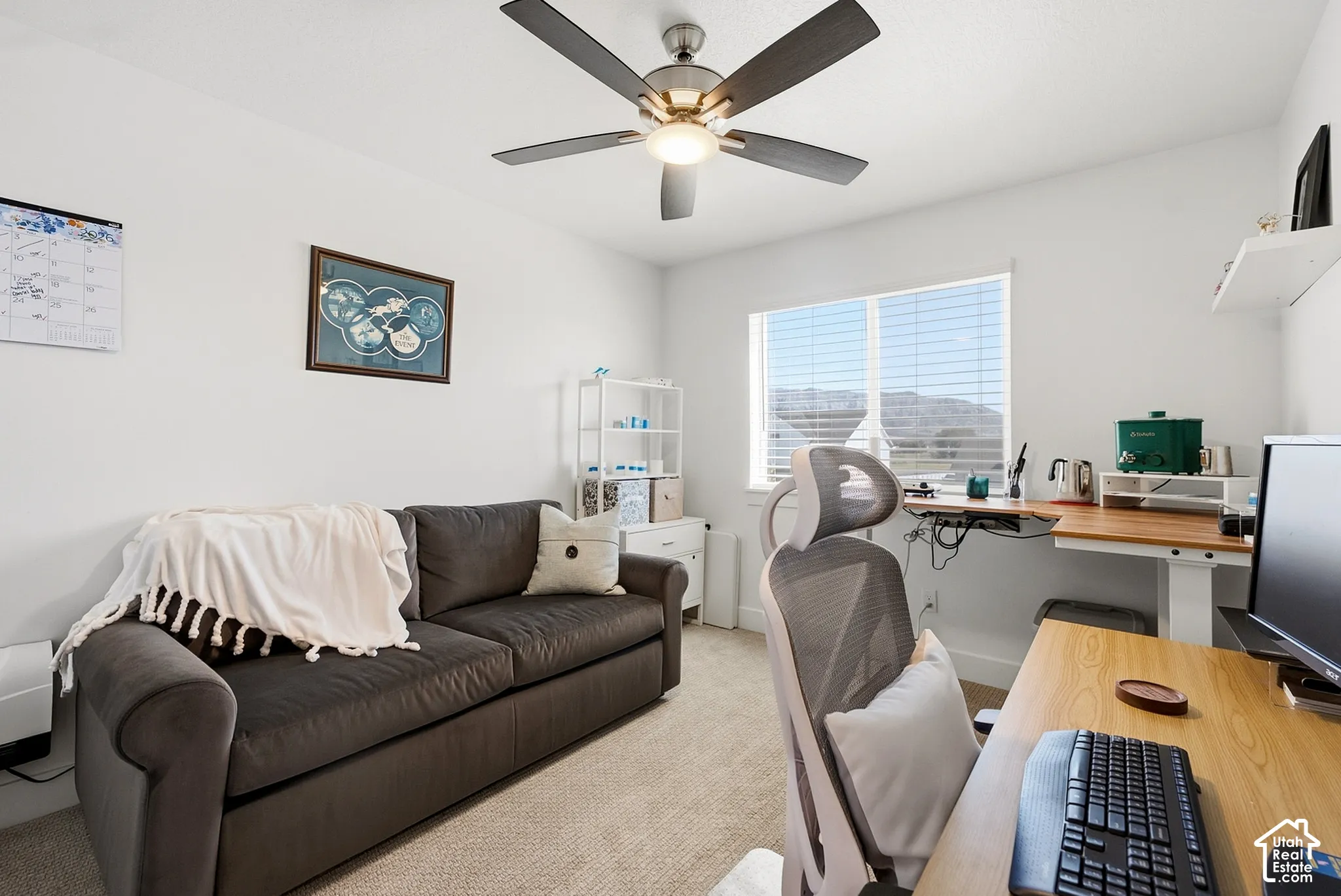 Bright room with a window featuring horizontal blinds, a ceiling fan with integrated lighting, and neutral carpeting