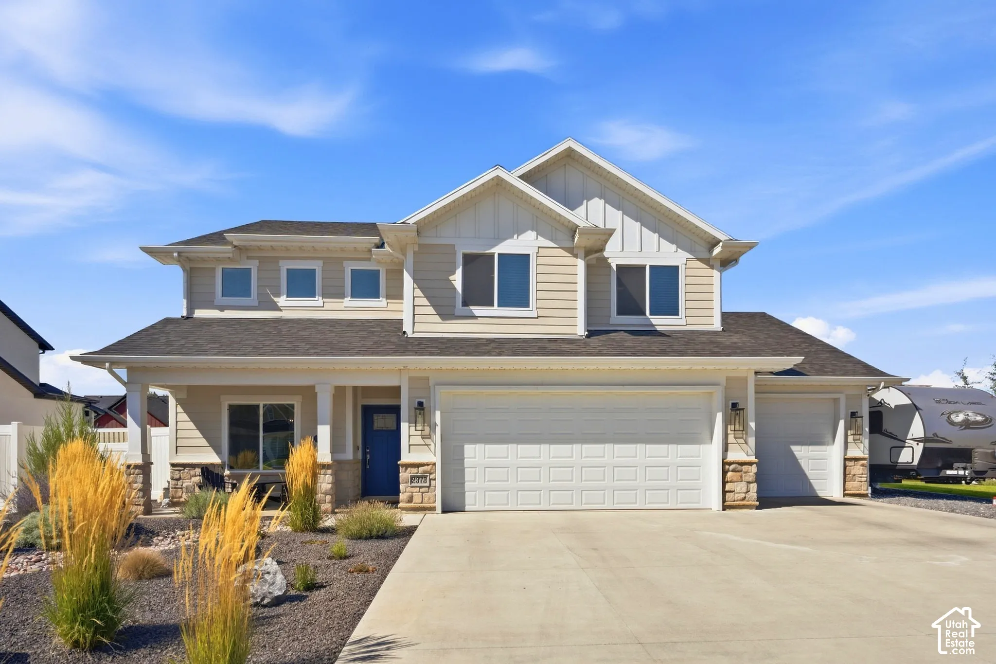Two-story residence featuring light-toned siding, a multi-car garage, and a covered porch