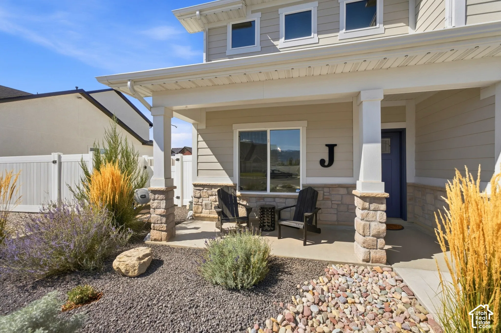 Inviting covered porch with stone-clad columns, surrounded by low-maintenance landscaping and decorative gravel