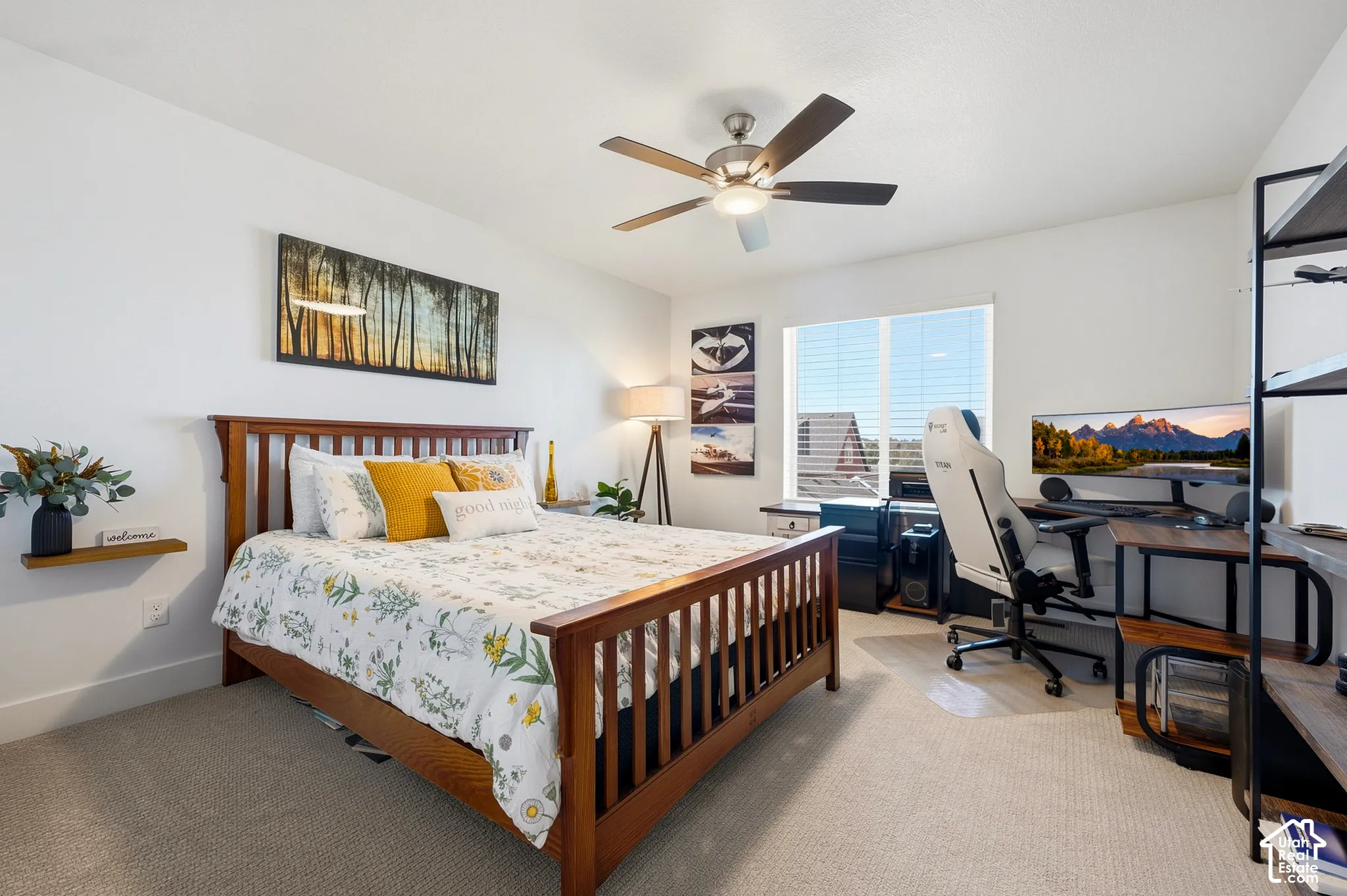 Carpeted flooring, ceiling fan with integrated lighting, window with horizontal blinds, and a built-in shelving unit