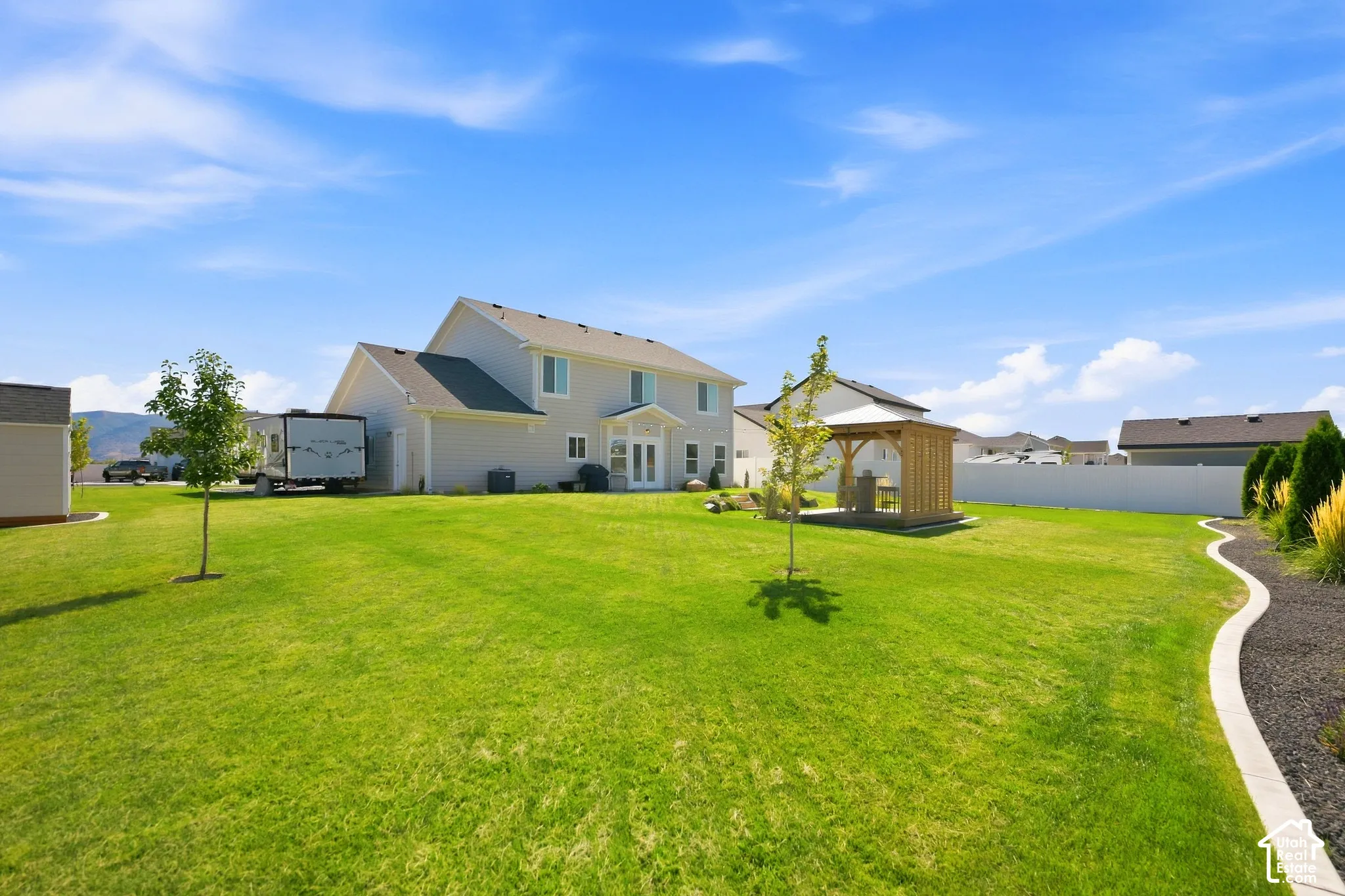 Expansive backyard with a manicured lawn, a detached gazebo structure, and a perimeter privacy fence