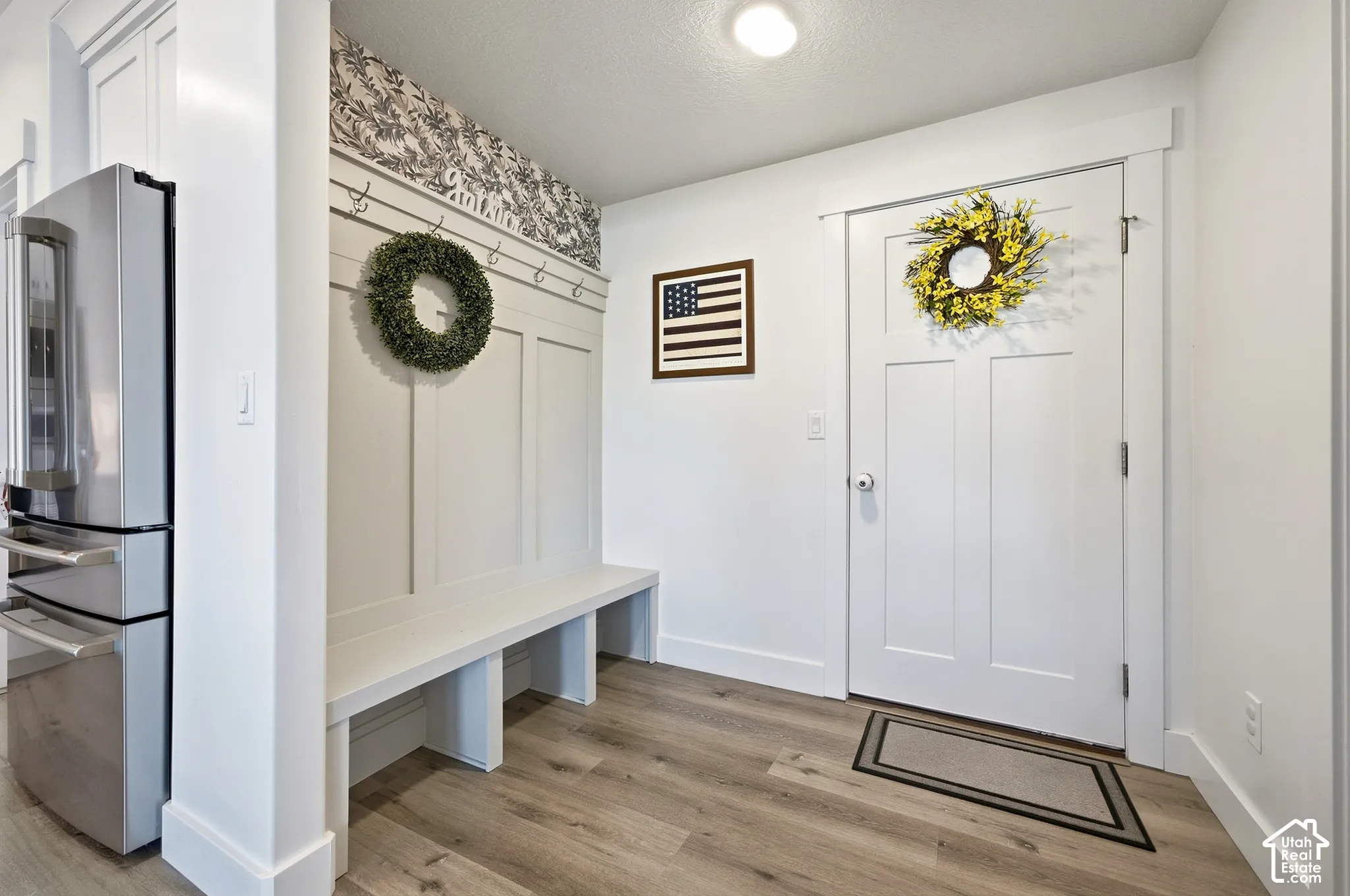 Entryway featuring wood-finish flooring, a built-in bench, and wall paneling