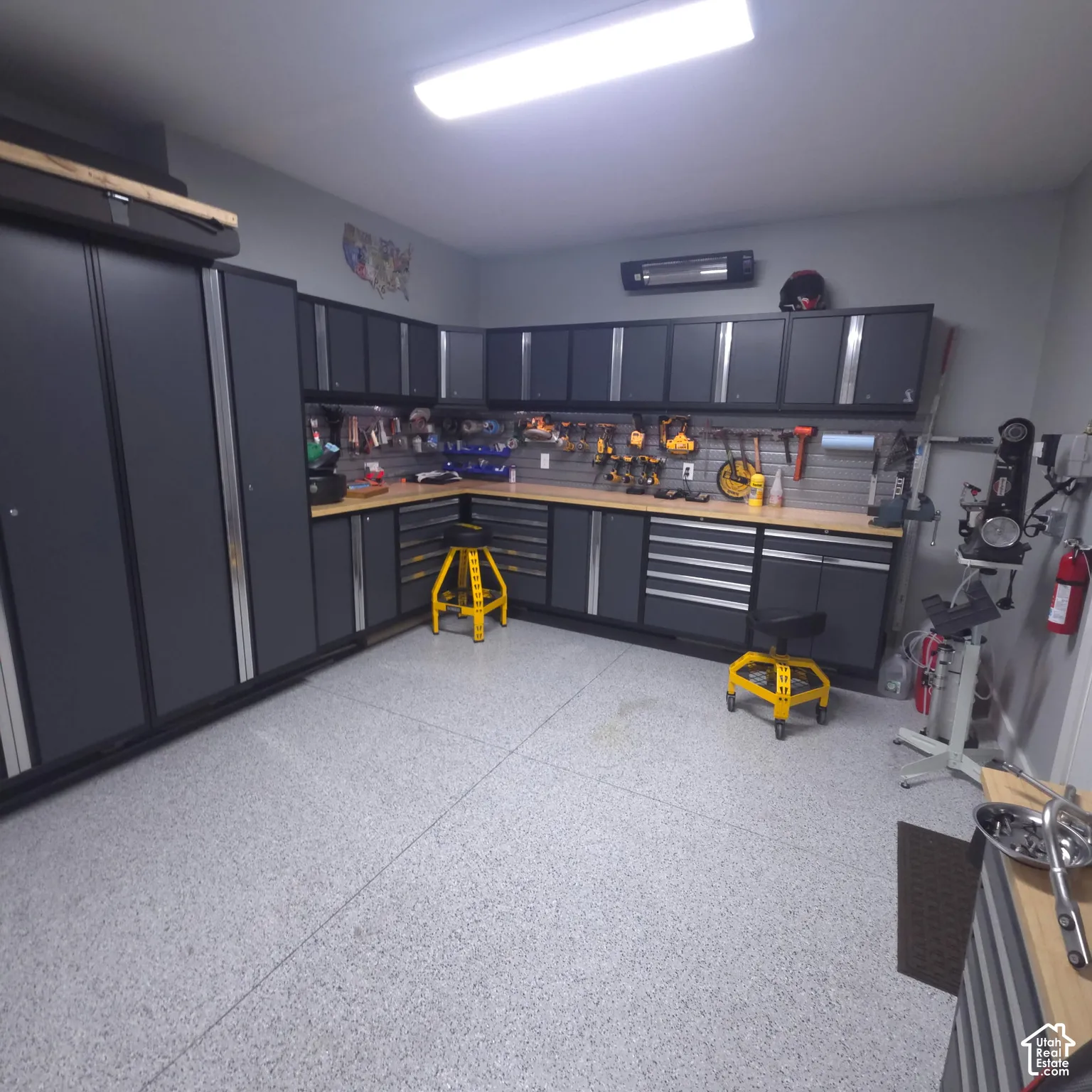 Garage featuring extensive cabinetry, integrated workbench, and a light-colored speckled floor finish