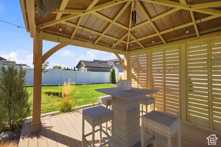 Outdoor gazebo with wood-finish decking, corrugated metal roof, and slatted wood privacy screens