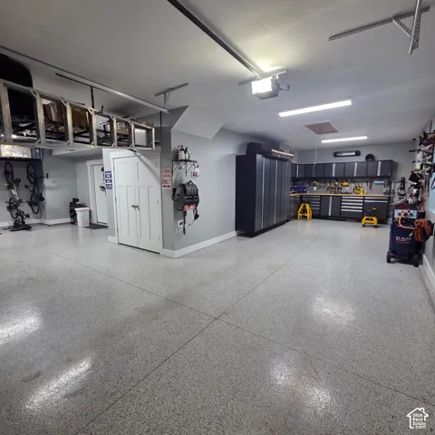 Epoxy flooring, extensive built-in cabinetry, overhead storage racks, recessed lighting, and a dedicated workbench area