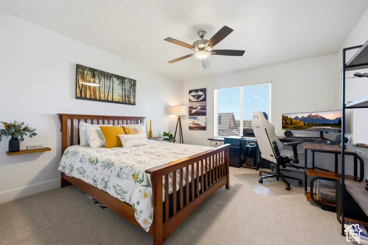 Carpeted flooring, ceiling fan with integrated lighting, window with horizontal blinds, and a built-in shelving unit