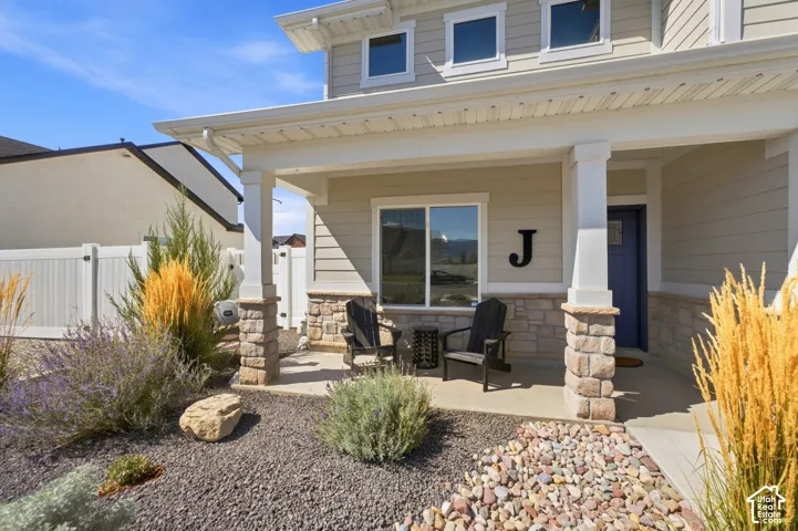 Inviting covered porch with stone-clad columns, surrounded by low-maintenance landscaping and decorative gravel