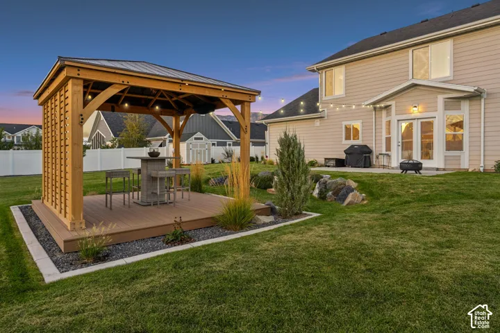Expansive backyard featuring a wood-finish gazebo with a metal roof, a composite deck, and a gravel border