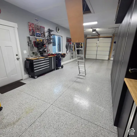 Epoxy finished flooring, overhead garage door, built-in storage cabinetry, built-in workbench, and wall-mounted storage organization