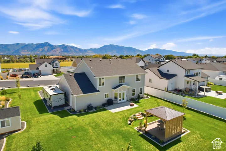 Expansive backyard featuring a gazebo with a metal roof, a manicured lawn, and a white privacy fence
